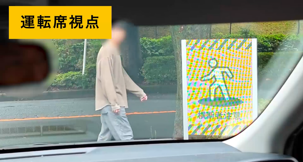 運転席から見た歩行者検知警報サイネージの実写映像。通行人が近づくとサイネージが点灯し、ドライバーへ視覚的に注意を促す